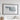 a large framed artwork depicting a snowy landscape, hanging on a white wall above a bed with white pillows.