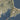 The image is a satellite view of a coastline with a river running through it. The coastline appears to be rocky and rugged, with a mix of land and water visible. The river is visible as a winding path that runs through the area.
