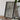 a wooden table with a framed photograph of a mountainous landscape, a camera, and a stack of books.