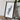 a framed map of Madagascar, a country in the South Pacific, placed on a wooden surface next to a camera and some books.