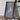 a framed map of Hawaii, a potted plant, a camera, and some books on a wooden table.