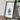 a framed map of Scotland, placed on a wooden surface next to a camera and some books.