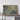 a large framed map of a coastal region, with a wooden shelf below it holding a camera and a book.