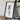 a framed map of a region, placed on a wooden surface next to a camera and some books.