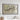 a large framed map hanging on a wall, depicting a mountainous landscape with a river or stream running through it.