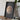 a framed picture of a planet, likely Mars, displayed on a wooden table. Next to the frame, there is a camera and a stack of books.