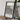 a framed artwork of a textured, abstract pattern on a wooden surface, with a camera and a stack of books nearby.