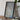 a large framed aerial map of a city, with a potted plant and a camera placed next to it on a wooden table.