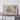 a large framed map of a mountainous region, with a wooden shelf below it.