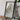 a framed map of Maine, with a camera and some books placed on a wooden table in front of it.
