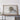 a large framed map of Alaska, with a wooden shelf below it holding a camera and a suitcase.