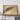 a large framed artwork depicting a desert landscape with sand dunes and a circular object in the center.