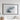 a large black framed picture hanging on a white wall, depicting a landscape with a mountain or hill.