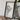 a framed map of South America, with a camera and some books placed on a wooden table in front of it.