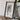 A framed map of the state of Kentucky, titled "Map of the state of Kentucky", is displayed on a wooden table next to a camera and some books.