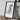 a framed map of the state of Louisiana, with a camera and some books placed on a wooden table in front of it.