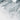 The image is a close-up of a textured surface, possibly a piece of fabric or paper, with a gray or white color scheme. The surface appears to be crumpled or wrinkled, giving it a somewhat rough or uneven appearance.
