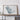 a large framed artwork depicting a map of Saudi Arabia, with a wooden shelf below it holding a camera and a book.