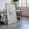 a large framed map of a region, with a wooden table and chairs in the background.