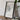 a framed map of a region, with a camera and some books placed on a wooden table in front of it.