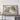 a large framed map of a mountainous region, with a wooden shelf below it.
