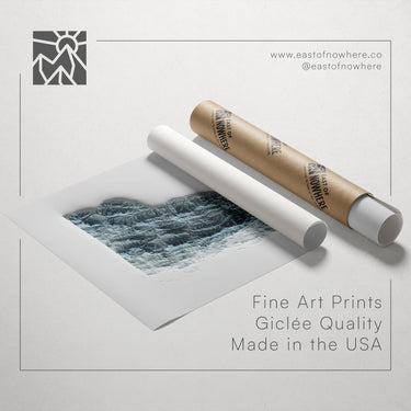 a roll of paper with a printed image of a mountain landscape, along with a tube of paper and a website address for fine art prints.