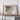 a large framed map of Arkansas hanging on a wall, with a wooden table and some personal items, such as a camera and a book, placed in front of it.