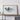 a large framed artwork depicting a mountainous landscape, placed on a wooden shelf against a white wall.