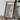 a framed map of the Cascade Range, with a camera and a book on a wooden table in front of it.