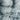 The image is a close-up of a textured, snowy surface, possibly a mountain or a rocky terrain. The surface appears to be covered in snow or ice, with a rough, uneven texture. There is no discernible text or countable objects in the image.