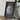 A framed image of the Earth is displayed on a wooden table, accompanied by a camera and some books.