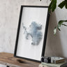 a framed map of Antarctica, placed on a wooden surface next to a camera and some books.