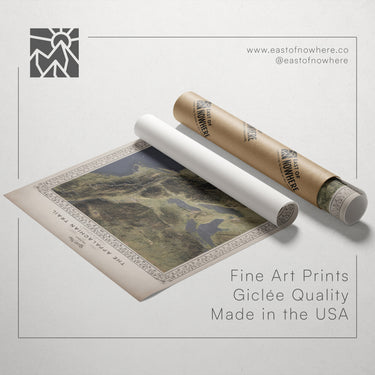 a roll of paper with a printed map of a mountainous region, along with a roll of paper and a cardboard tube.