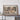 a large framed map of the Himalayan region, with a wooden shelf below it holding a camera and some books.