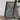 a framed map of a region, a camera, and some books on a wooden table.