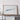 a large framed artwork depicting a mountain landscape, placed on a wooden shelf against a white wall.