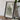 a framed map of a mountainous region, with a camera and some books placed on a wooden table in front of it.