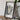 A framed map of Cape Coral, Florida, is displayed on a wooden surface next to a camera and some books.