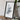 a framed map of a region, placed on a wooden surface next to a camera and some books.
