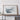 a large framed map of a mountainous region, displayed on a wooden shelf against a white wall.