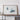a large framed artwork depicting two abstract shapes, one resembling a leaf and the other a cloud, displayed on a wooden shelf against a white wall.