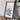 a framed map of Germany placed on a wooden surface, with a camera and some books nearby.