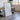 a large white framed artwork displayed on a wooden table in a room with a brick wall and a window.