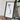a framed map of Vietnam, placed on a wooden surface next to a camera and some books.